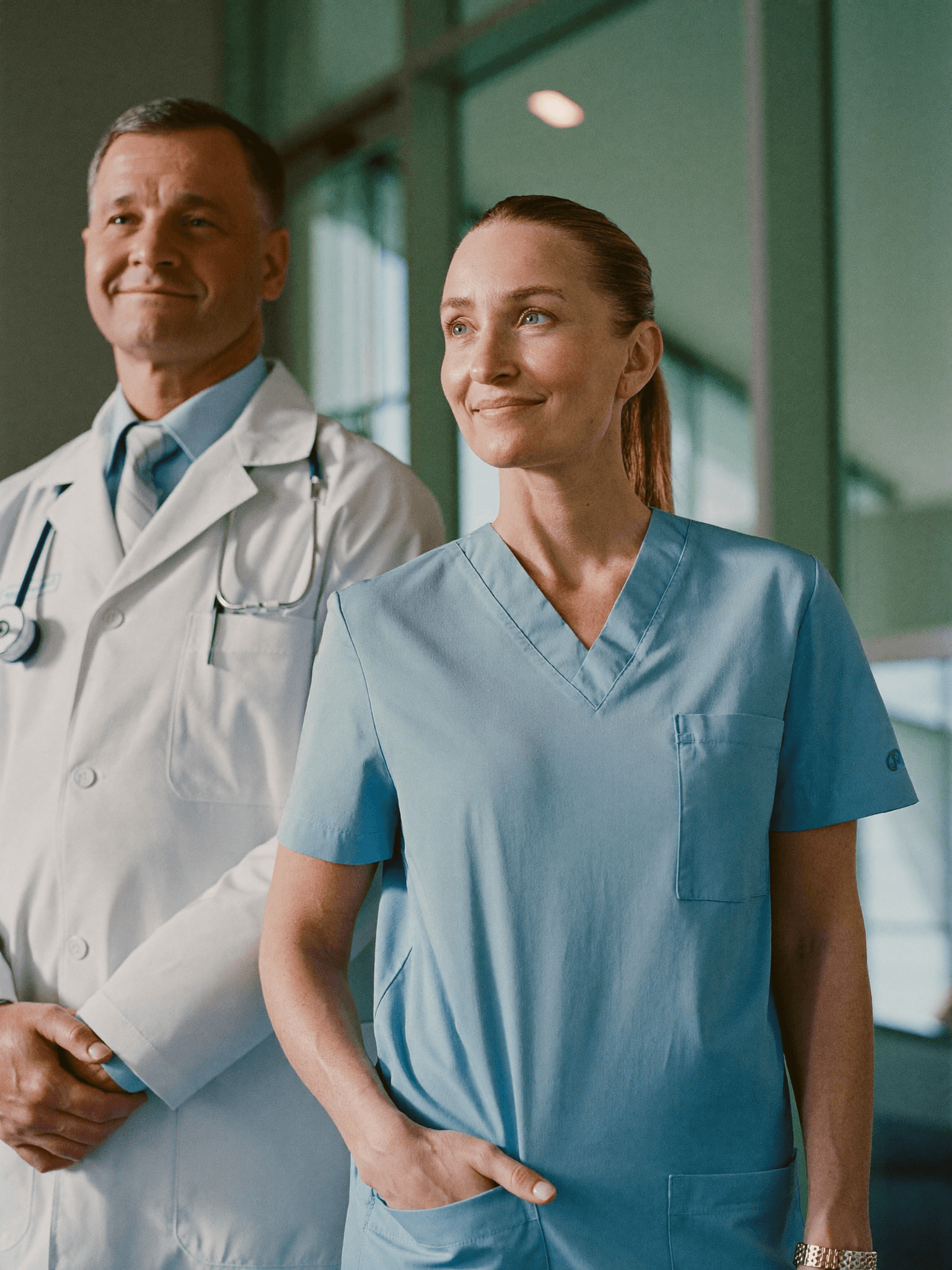 A doctor and nurse standing together in a bright healthcare facility